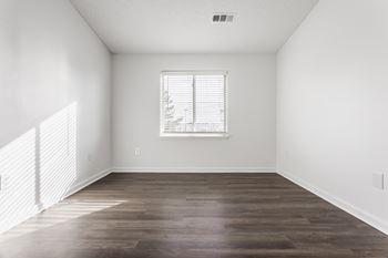 An empty living room with white walls and a window